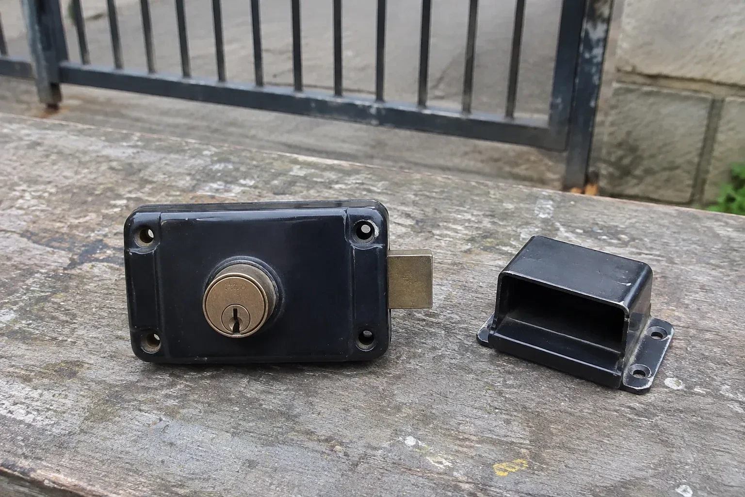 Detached rim gate lock and separate box keeper on an outdoor workbench. — Gate & Building Entry Locks, Mohawk Meadows